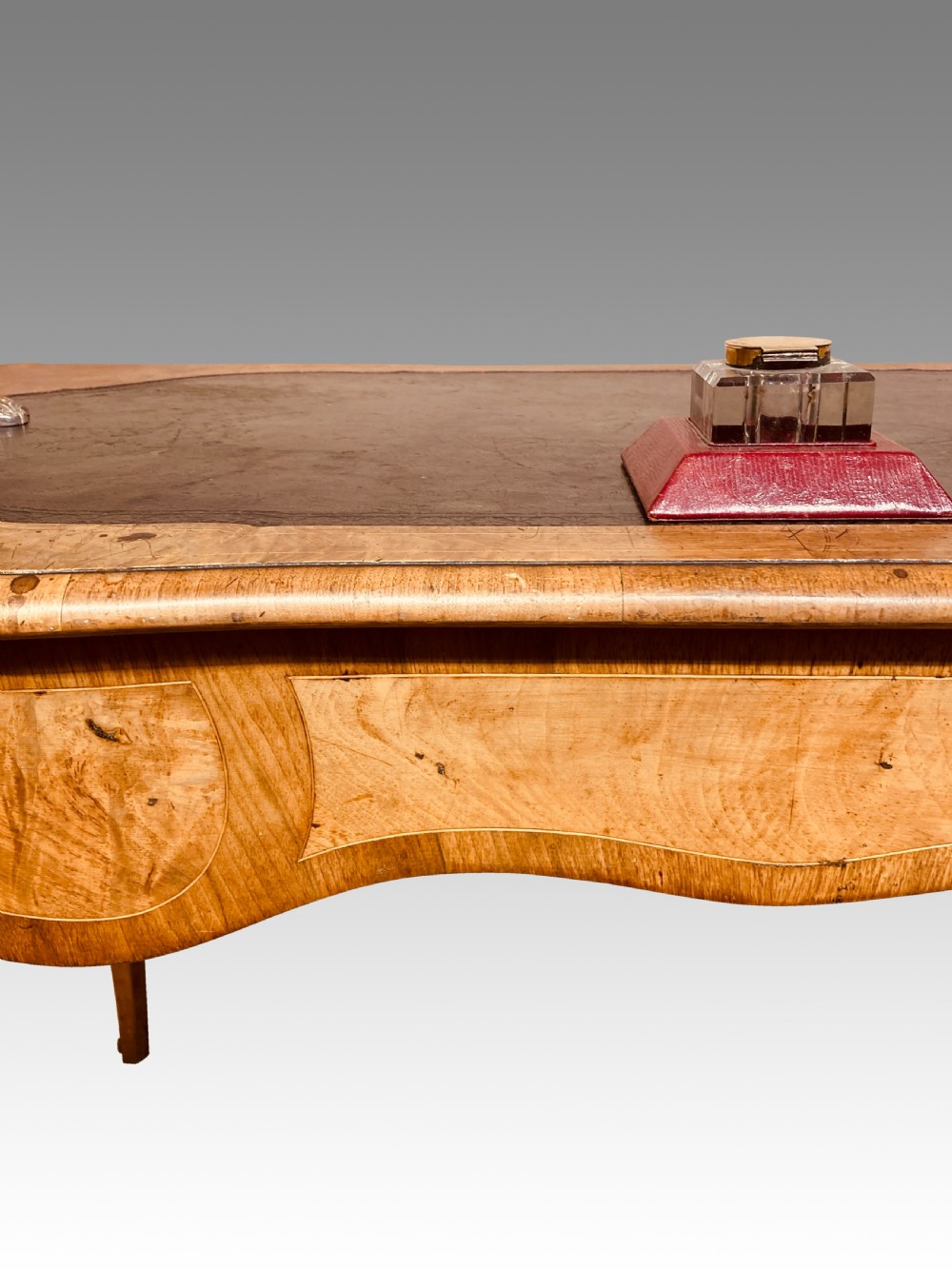 A Victorian burr walnut writing table featuring cabriole legs, ornate gilt-bronze mounts, a serpentine apron, and a dark leather inset writing surface. View II