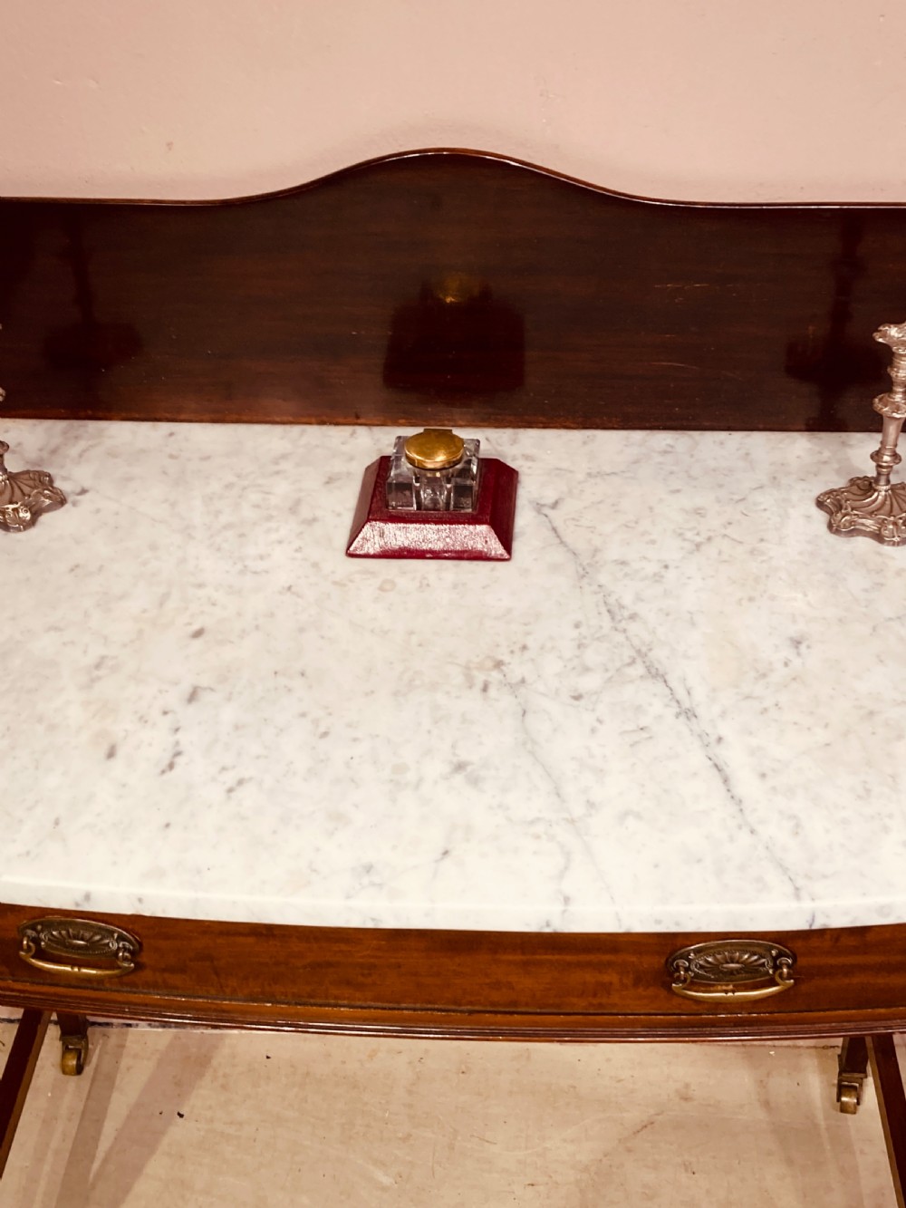 A 19th-century mahogany bow-fronted side table featuring a white marble top, a wooden gallery back, a single drawer with brass handles, and slender tapered legs on castors. View III