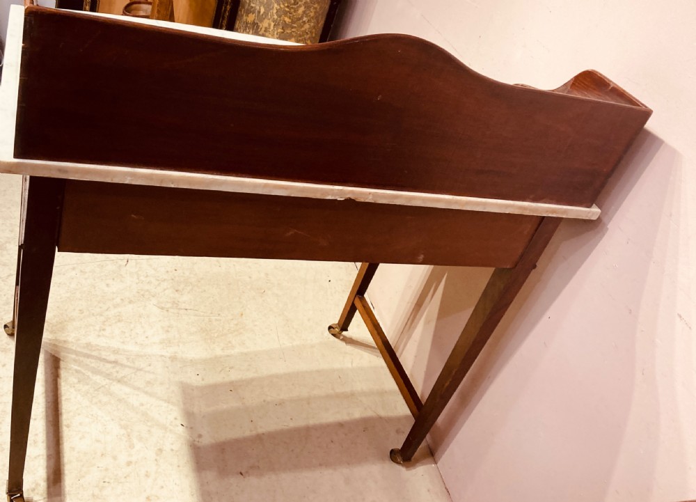 A 19th-century mahogany bow-fronted side table featuring a white marble top, a wooden gallery back, a single drawer with brass handles, and slender tapered legs on castors. View VIII