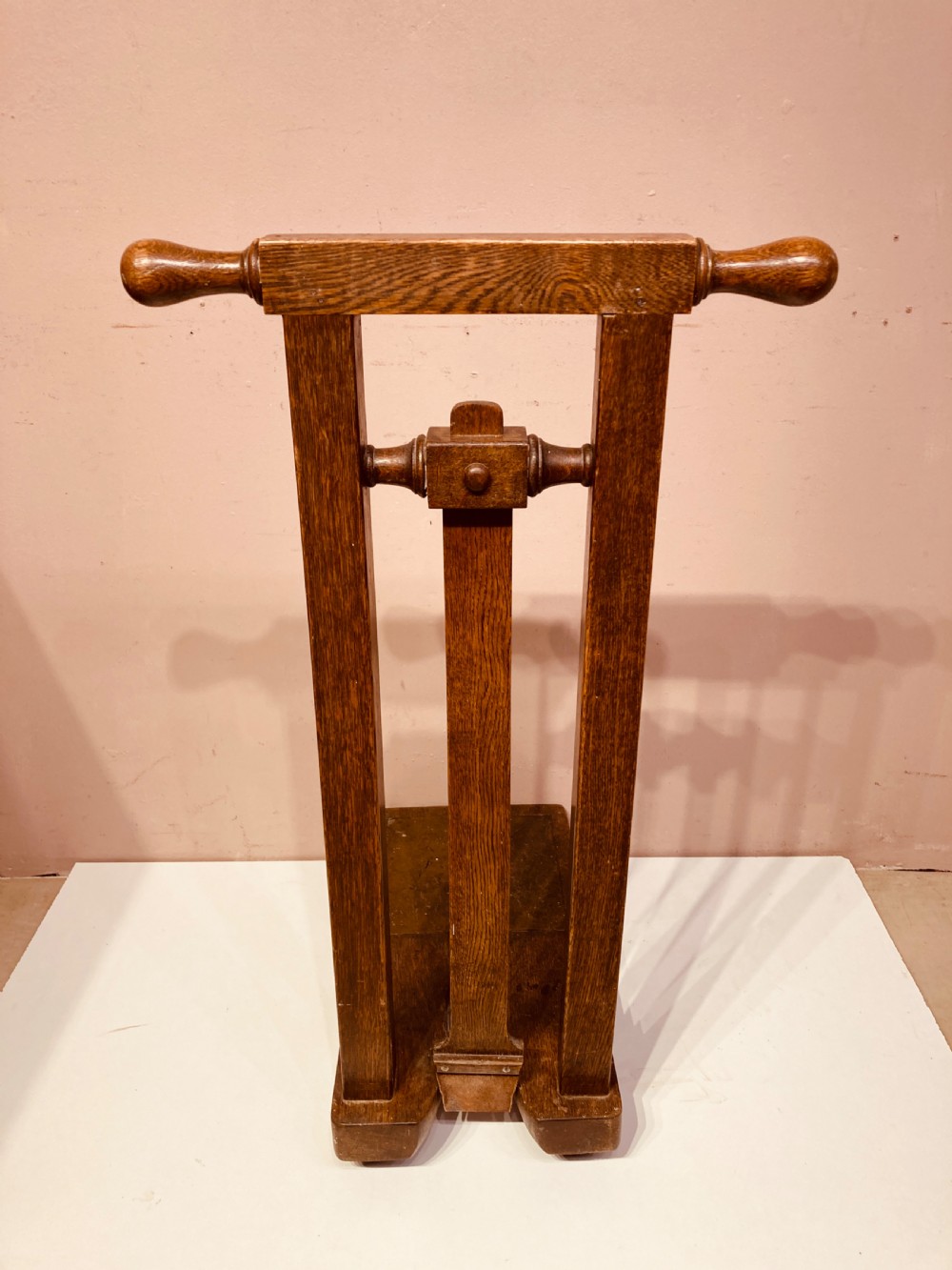 An antique freestanding oak boot jack featuring two top handles, a central vertical column, and a heel removal slot at the base. View II