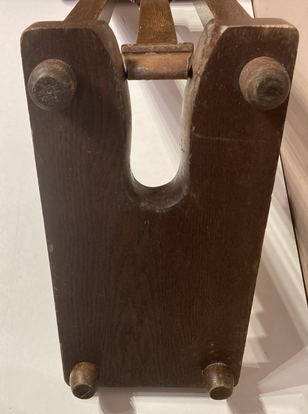 An antique freestanding oak boot jack featuring two top handles, a central vertical column, and a heel removal slot at the base. View VI