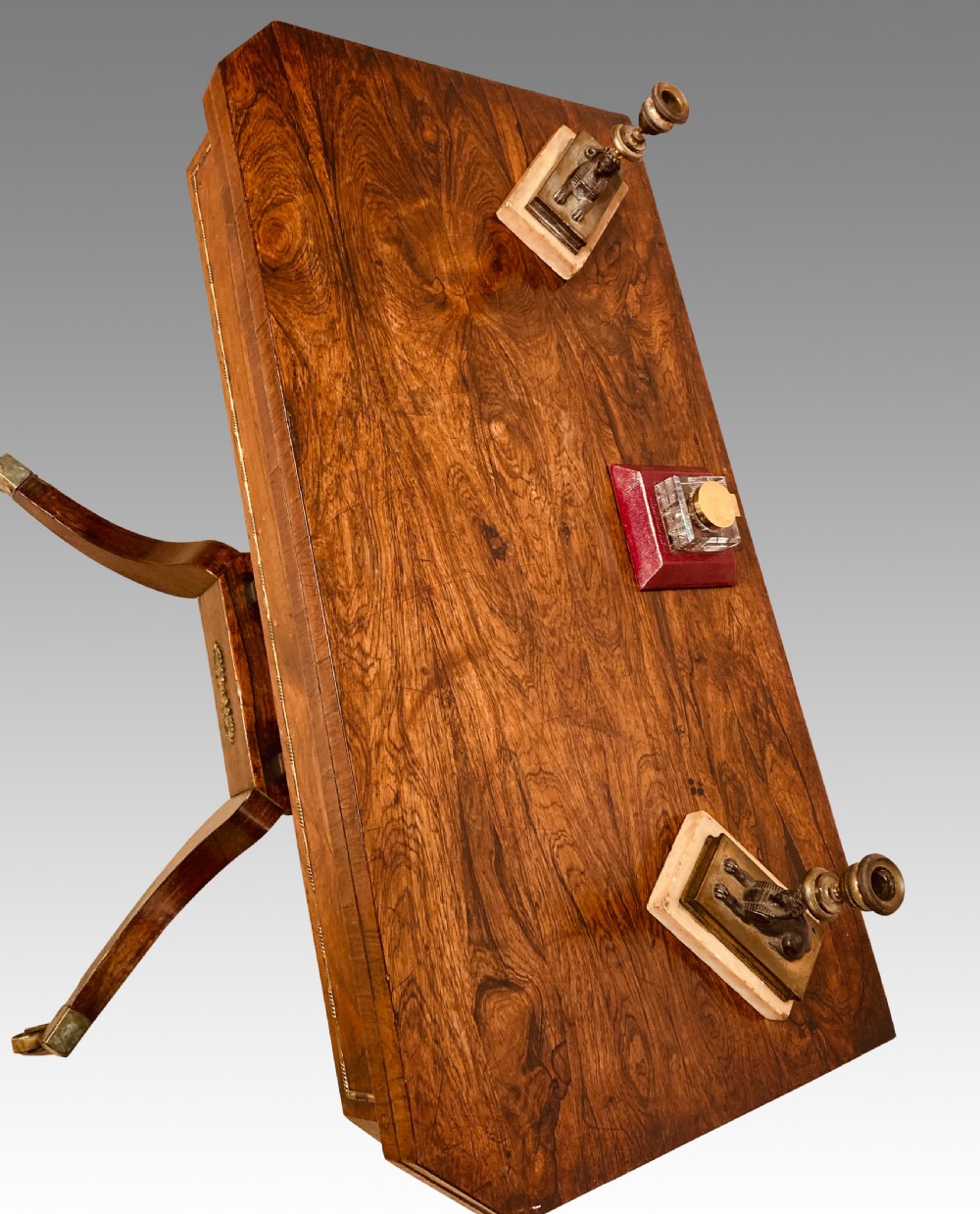 A Regency rosewood fold-over card table featuring brass inlay, a central pedestal support, and four curved sabre legs on brass castors. View II