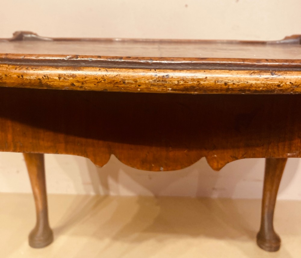 An oval burr walnut coffee table featuring a shaped tray rim and carved cabriole legs ending in pad feet. View II