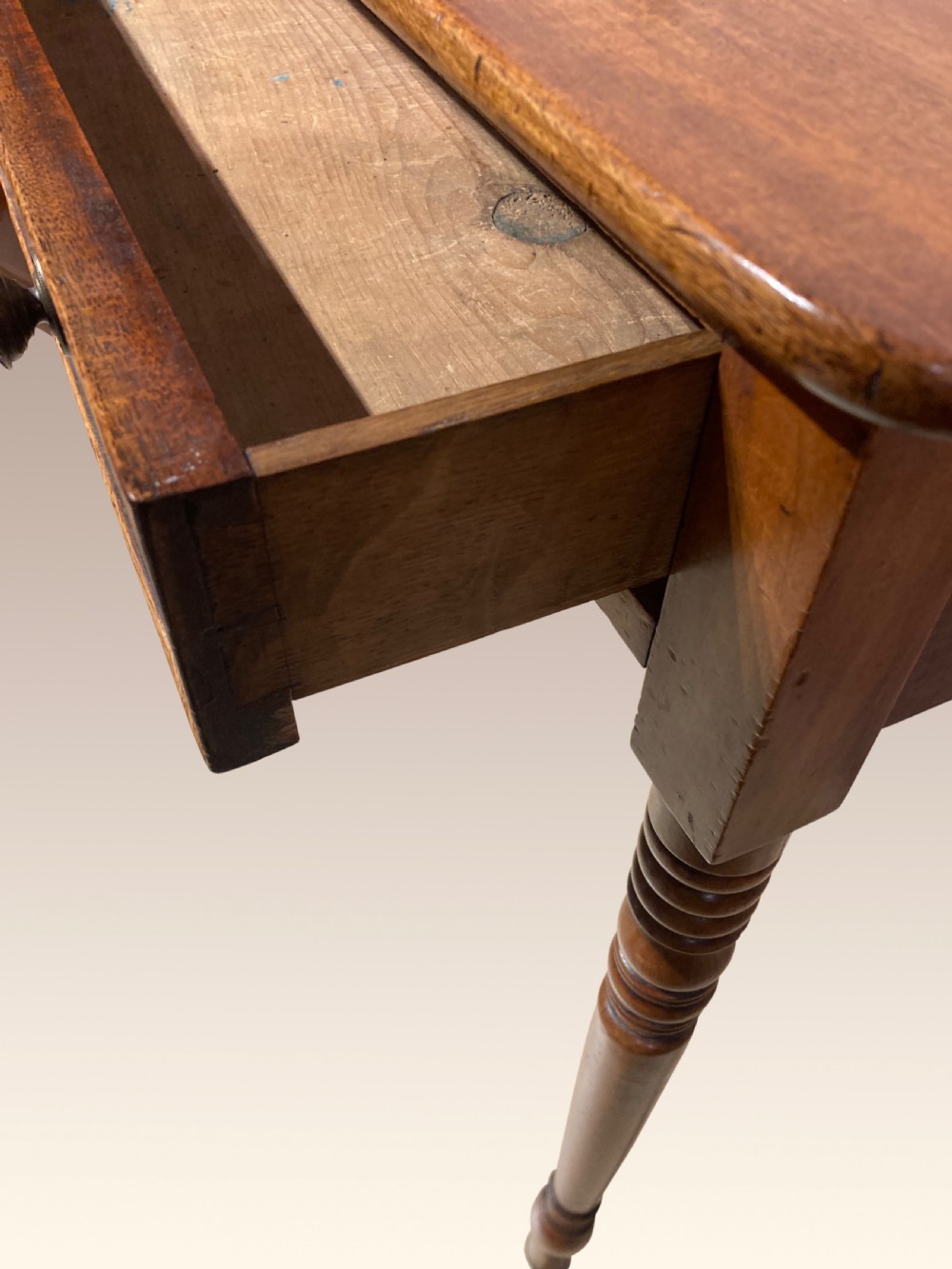 A Georgian mahogany writing table featuring a single drawer with two brass knobs, slender turned legs, and brass castors. View IV
