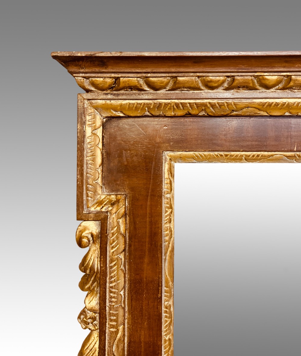A rectangular 19th-century wall mirror crafted with polished mahogany veneer, bordered by carved gold giltwood trim and featuring a scalloped lower apron. View IV