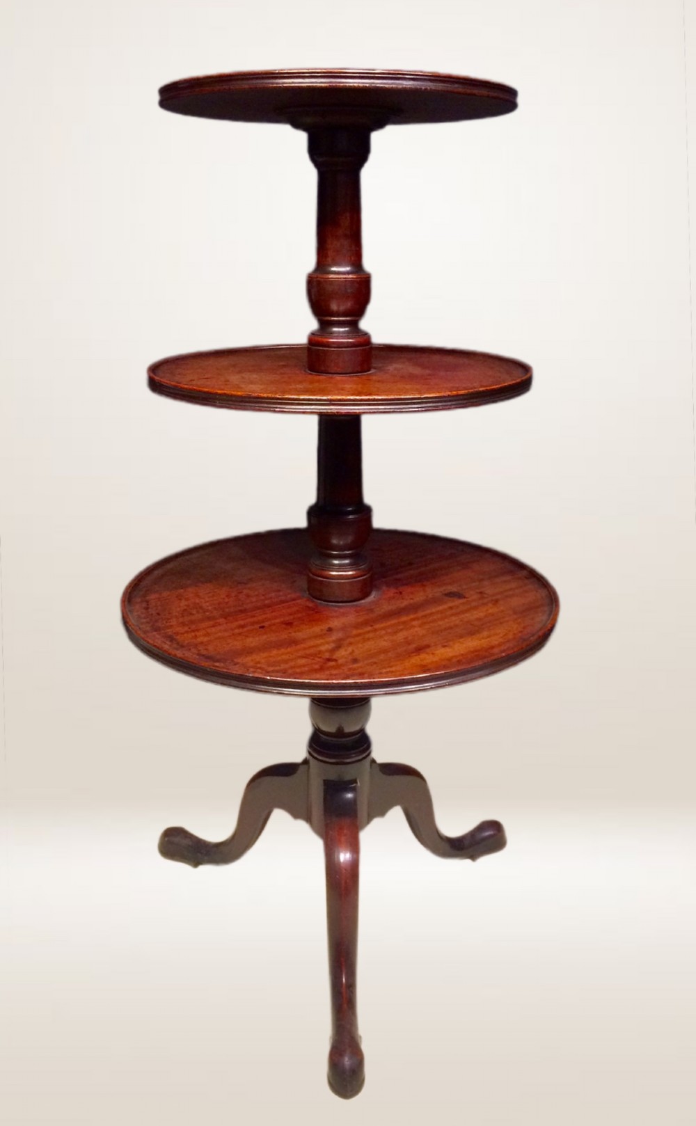 A three-tiered Georgian mahogany dumb waiter featuring graduated circular trays supported by a turned column and tripod base. View II