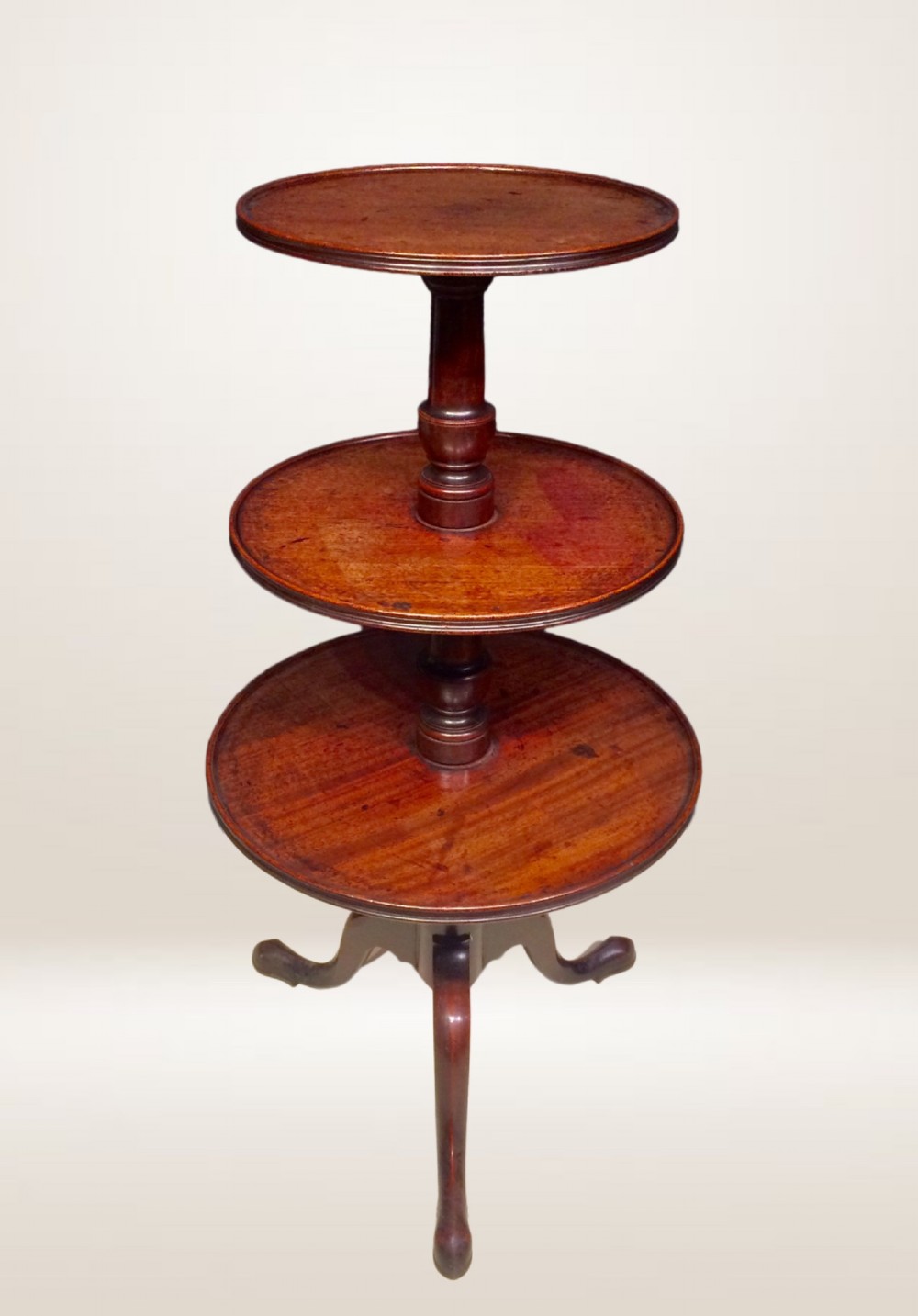 A three-tiered Georgian mahogany dumb waiter featuring graduated circular trays supported by a turned column and tripod base. View VI