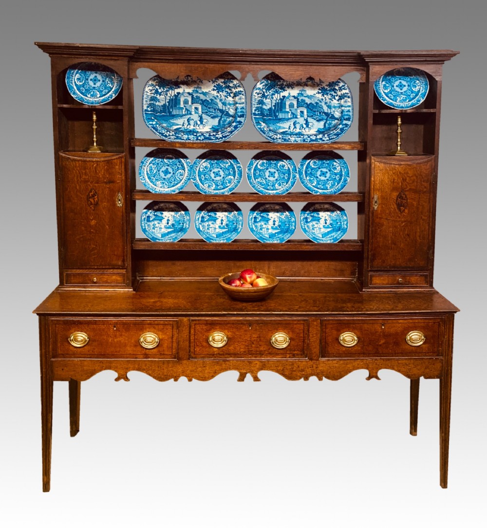 A Georgian oak Shropshire dresser featuring an open plate rack with side cupboards above a three-drawer base on tapered legs.