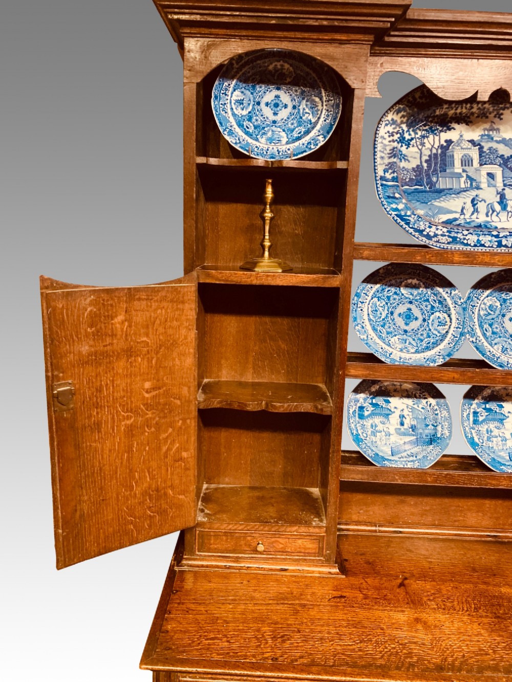 A Georgian oak Shropshire dresser featuring an open plate rack with side cupboards above a three-drawer base on tapered legs. View II