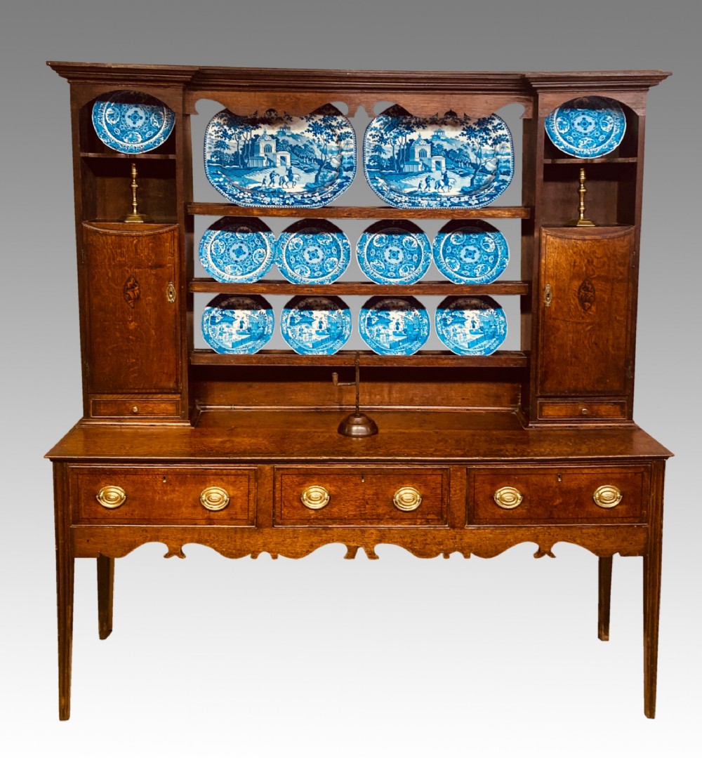 A Georgian oak Shropshire dresser featuring an open plate rack with side cupboards above a three-drawer base on tapered legs. View III