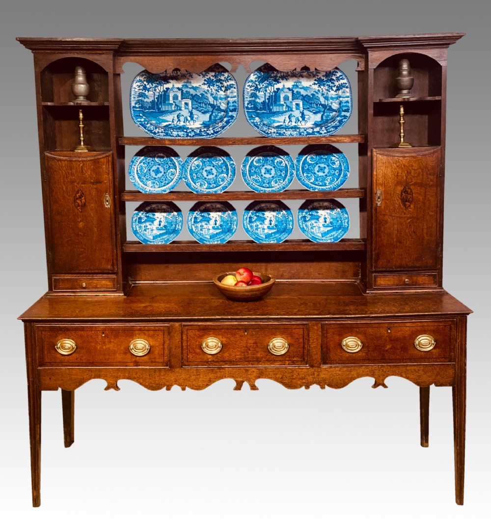 A Georgian oak Shropshire dresser featuring an open plate rack with side cupboards above a three-drawer base on tapered legs. View V