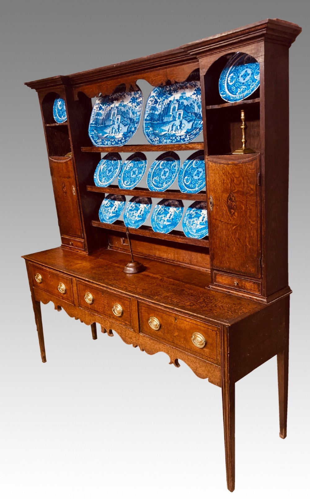A Georgian oak Shropshire dresser featuring an open plate rack with side cupboards above a three-drawer base on tapered legs. View VI