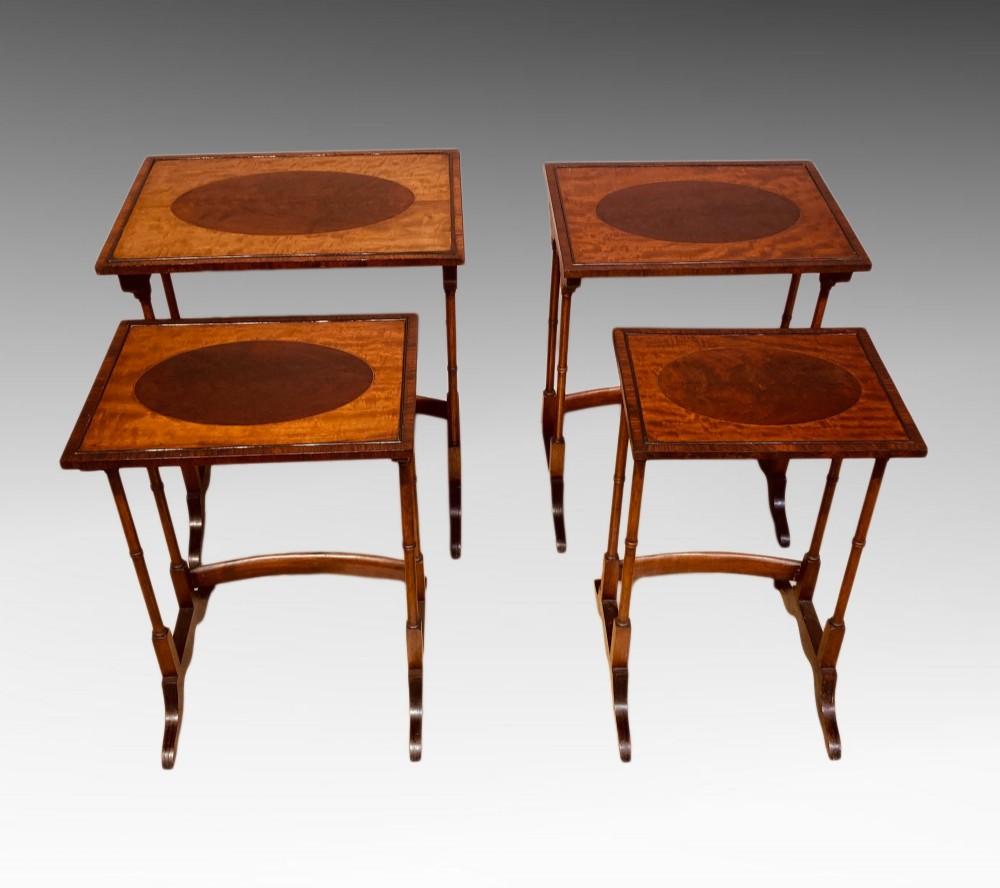 A set of four graduated mahogany nesting tables featuring oval satinwood centre inlays and slim turned dual-spindle legs. View II
