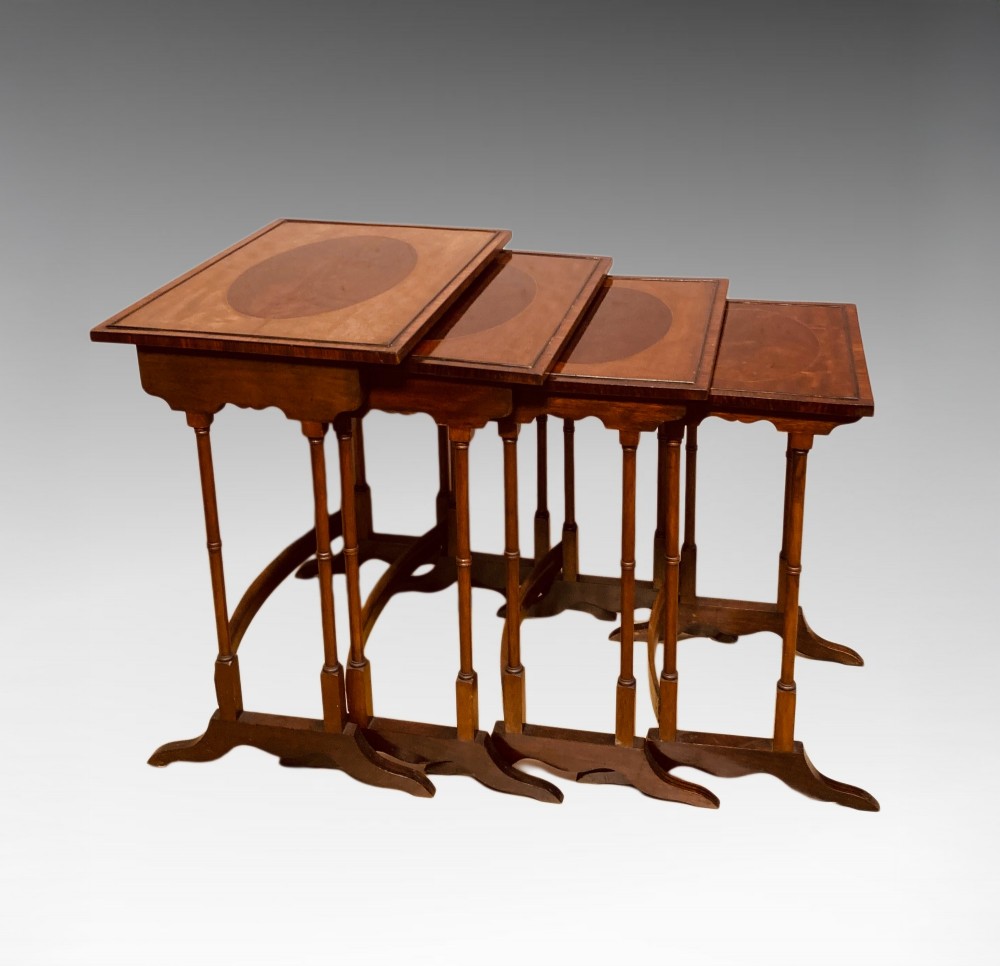 A set of four graduated mahogany nesting tables featuring oval satinwood centre inlays and slim turned dual-spindle legs. View III
