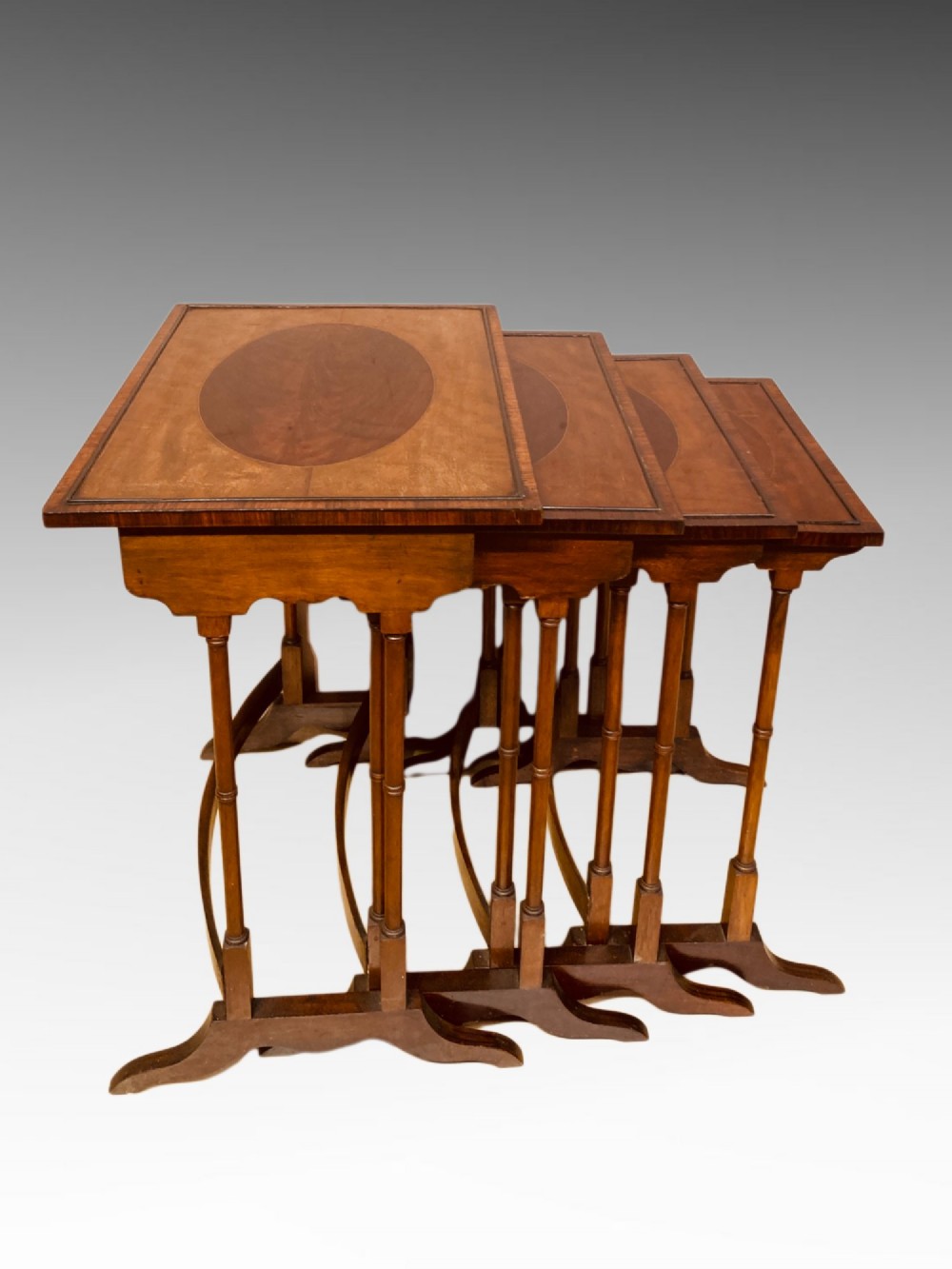 A set of four graduated mahogany nesting tables featuring oval satinwood centre inlays and slim turned dual-spindle legs. View IV