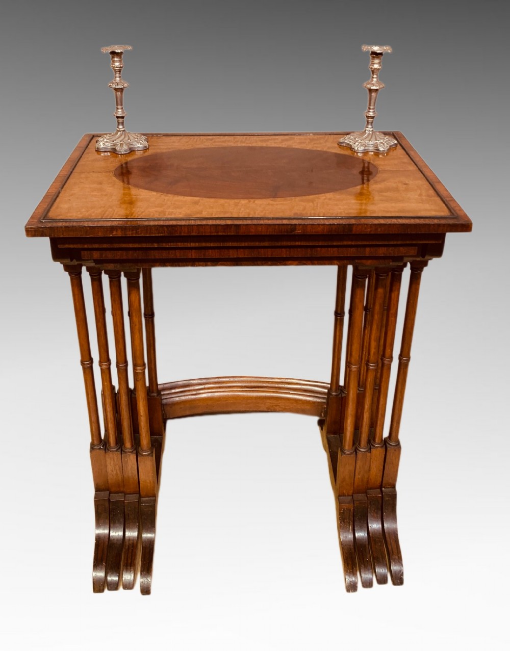 A set of four graduated mahogany nesting tables featuring oval satinwood centre inlays and slim turned dual-spindle legs. View VII