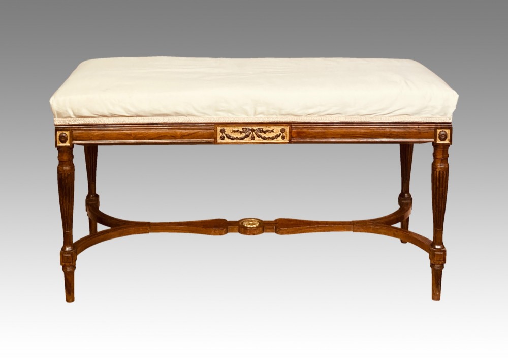 A 19th-century rosewood rectangular music bench featuring a cream upholstered seat, fluted legs, and a gilt decorative central panel on the frieze.