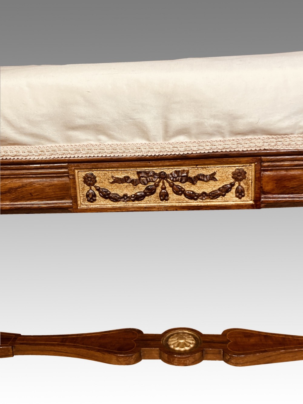 A 19th-century rosewood rectangular music bench featuring a cream upholstered seat, fluted legs, and a gilt decorative central panel on the frieze. View IV