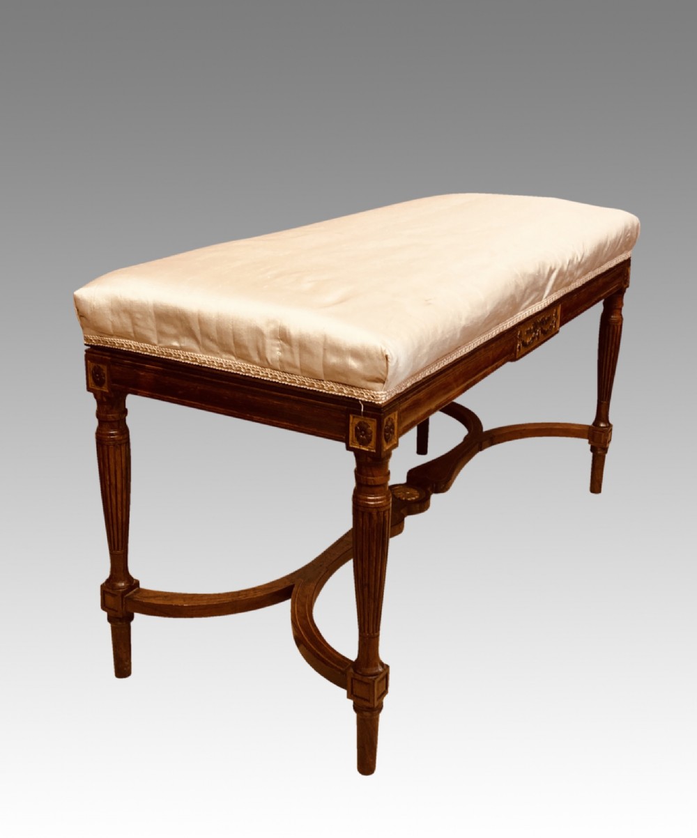 A 19th-century rosewood rectangular music bench featuring a cream upholstered seat, fluted legs, and a gilt decorative central panel on the frieze. View VII