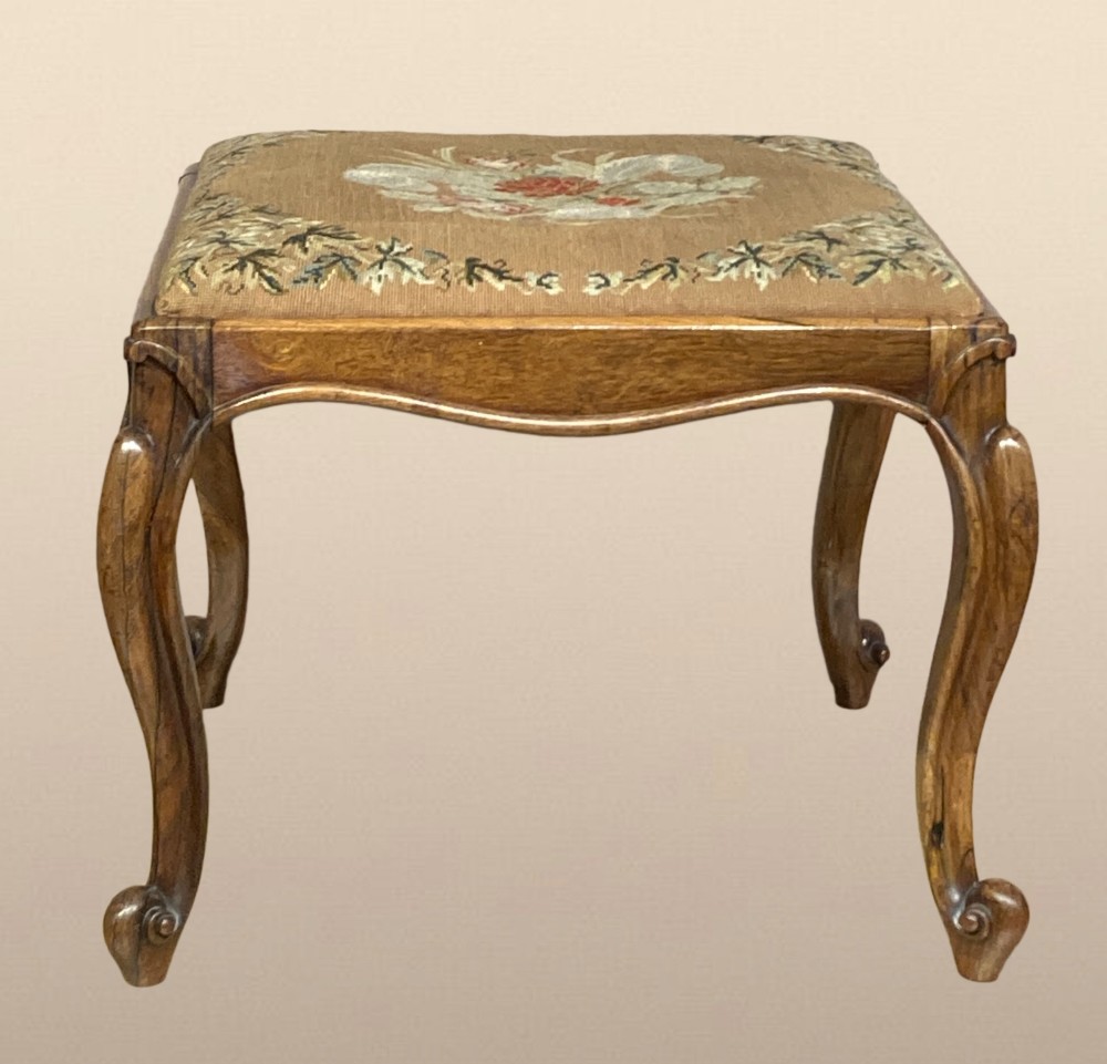 A Victorian rosewood dressing stool featuring carved cabriole legs and a floral needlepoint upholstered seat.
