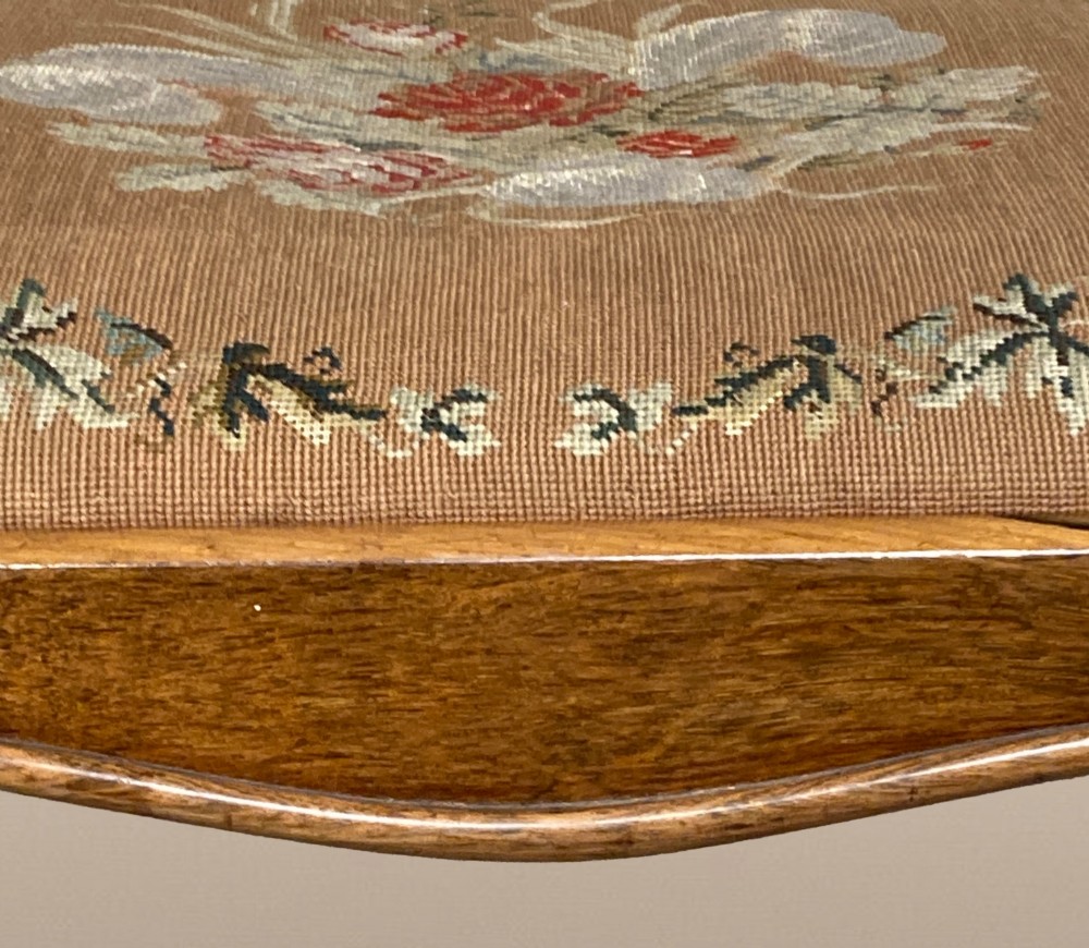 A Victorian rosewood dressing stool featuring carved cabriole legs and a floral needlepoint upholstered seat. View VII