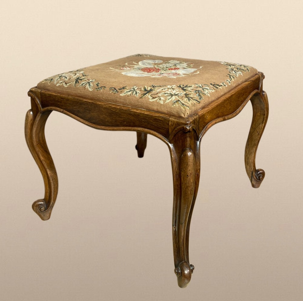 A Victorian rosewood dressing stool featuring carved cabriole legs and a floral needlepoint upholstered seat. View VIII