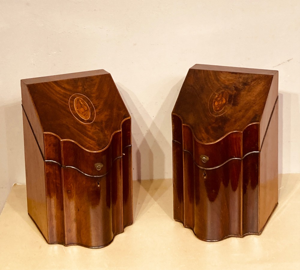 A pair of Georgian mahogany knife boxes featuring sloping lids with oval marquetry shell inlays and serpentine-fronted bodies.