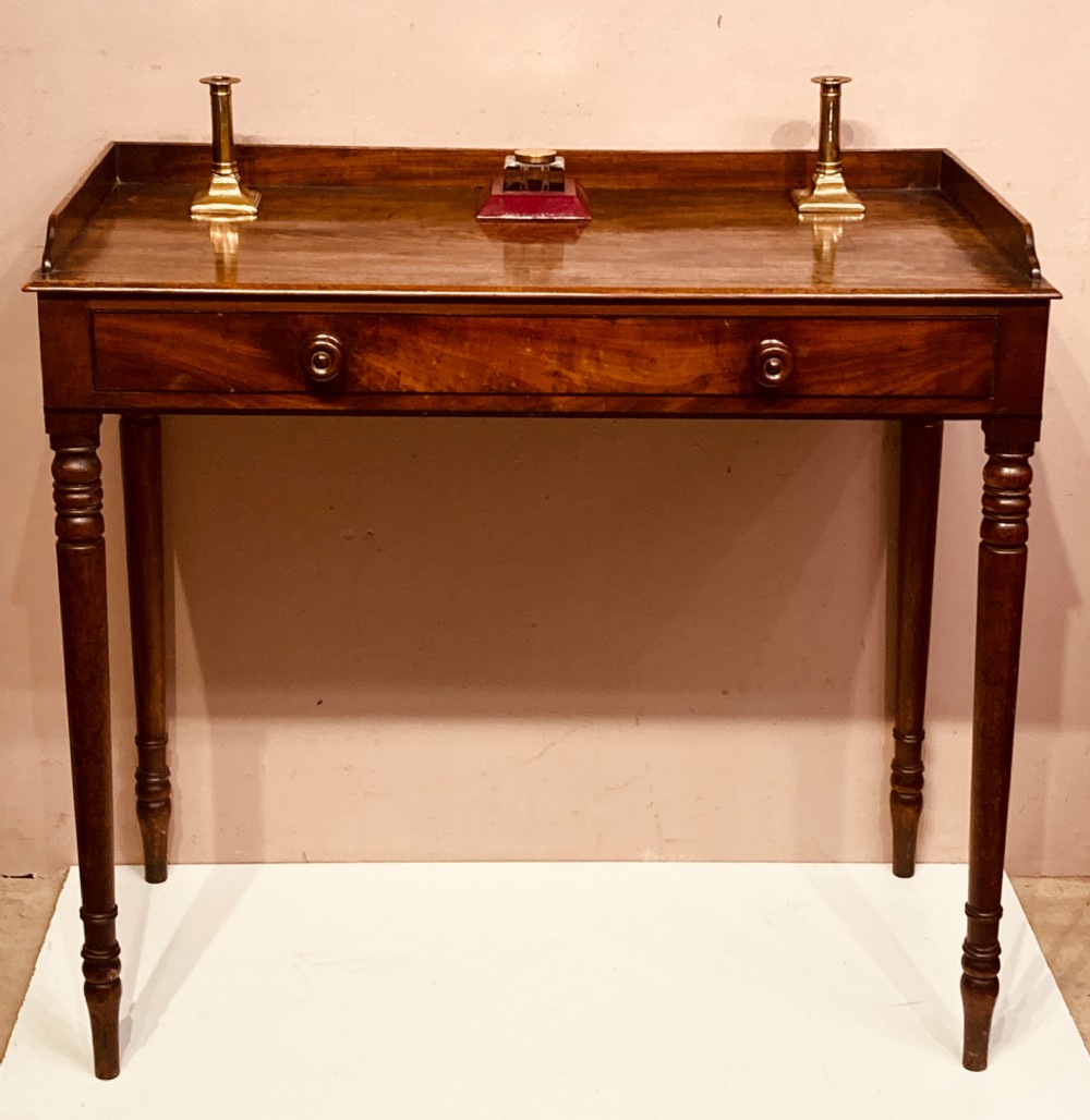 A Georgian mahogany side table featuring a raised gallery top, turned legs, and a single frieze drawer.