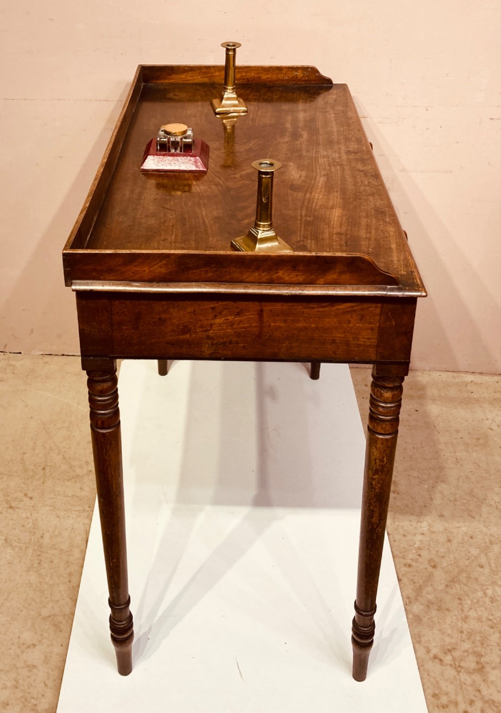 A Georgian mahogany side table featuring a raised gallery top, turned legs, and a single frieze drawer. View V
