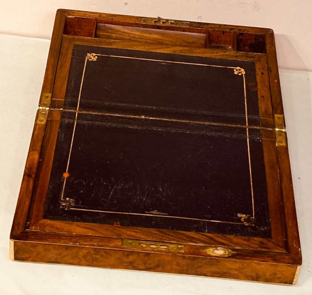 A rectangular Late Georgian burr walnut writing slope box featuring brass edging, an oval brass lid plaque, and a keyhole with key on the front. View V