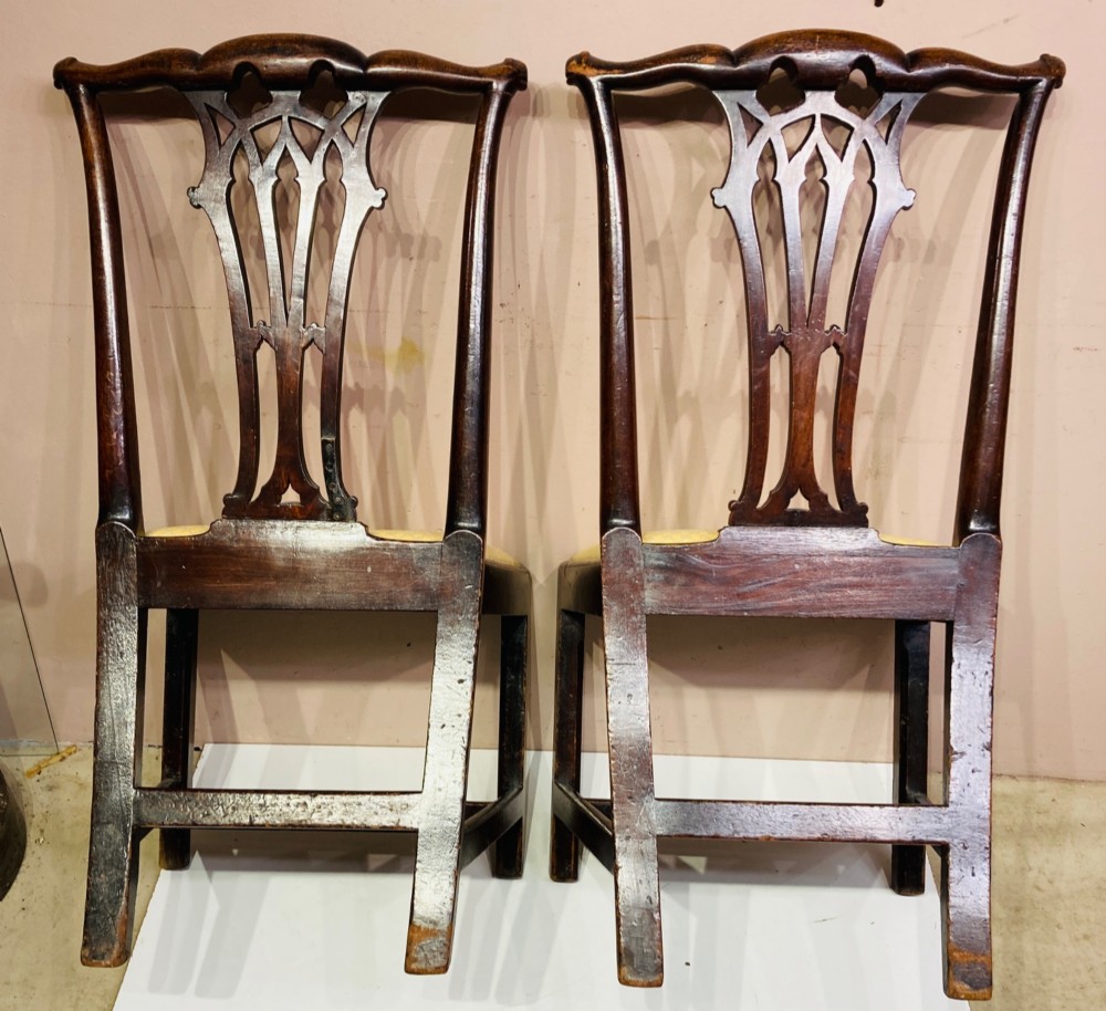 A pair of antique Georgian mahogany side chairs featuring pierced Gothic splat backs, cream upholstered seats, and straight legs connected by stretchers. View III
