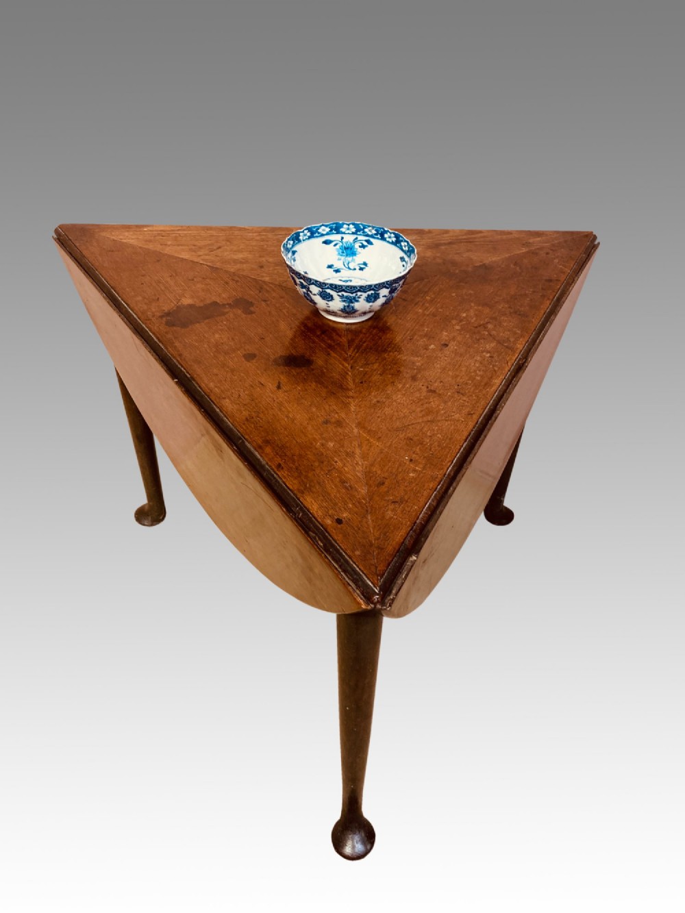 A Georgian red walnut drop-leaf table featuring a triangular top, drop flaps, and turned legs ending in pad feet. View II