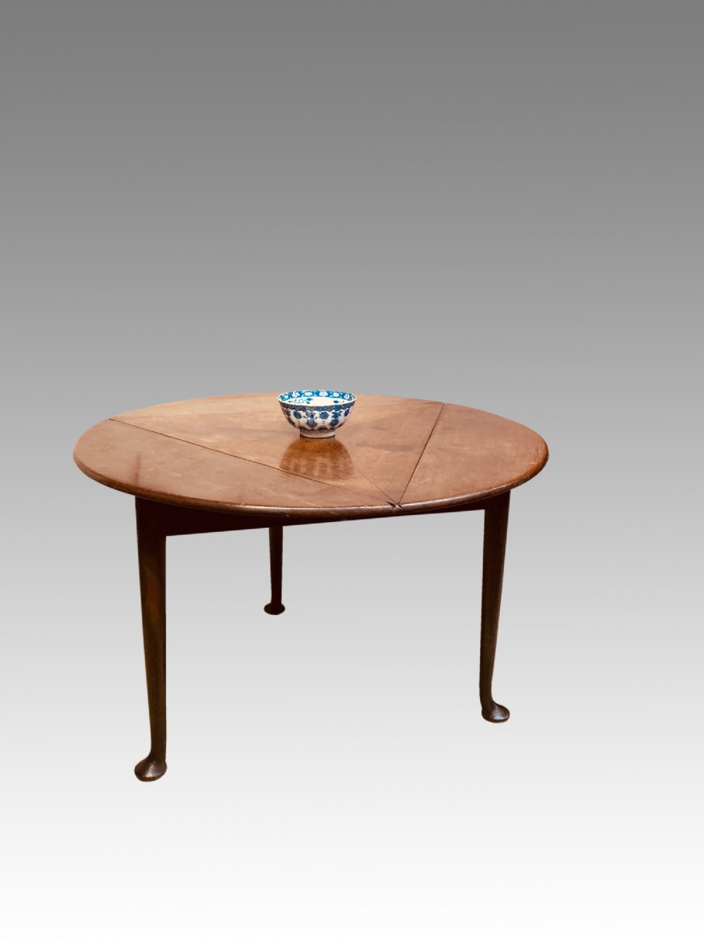 A Georgian red walnut drop-leaf table featuring a triangular top, drop flaps, and turned legs ending in pad feet. View VI