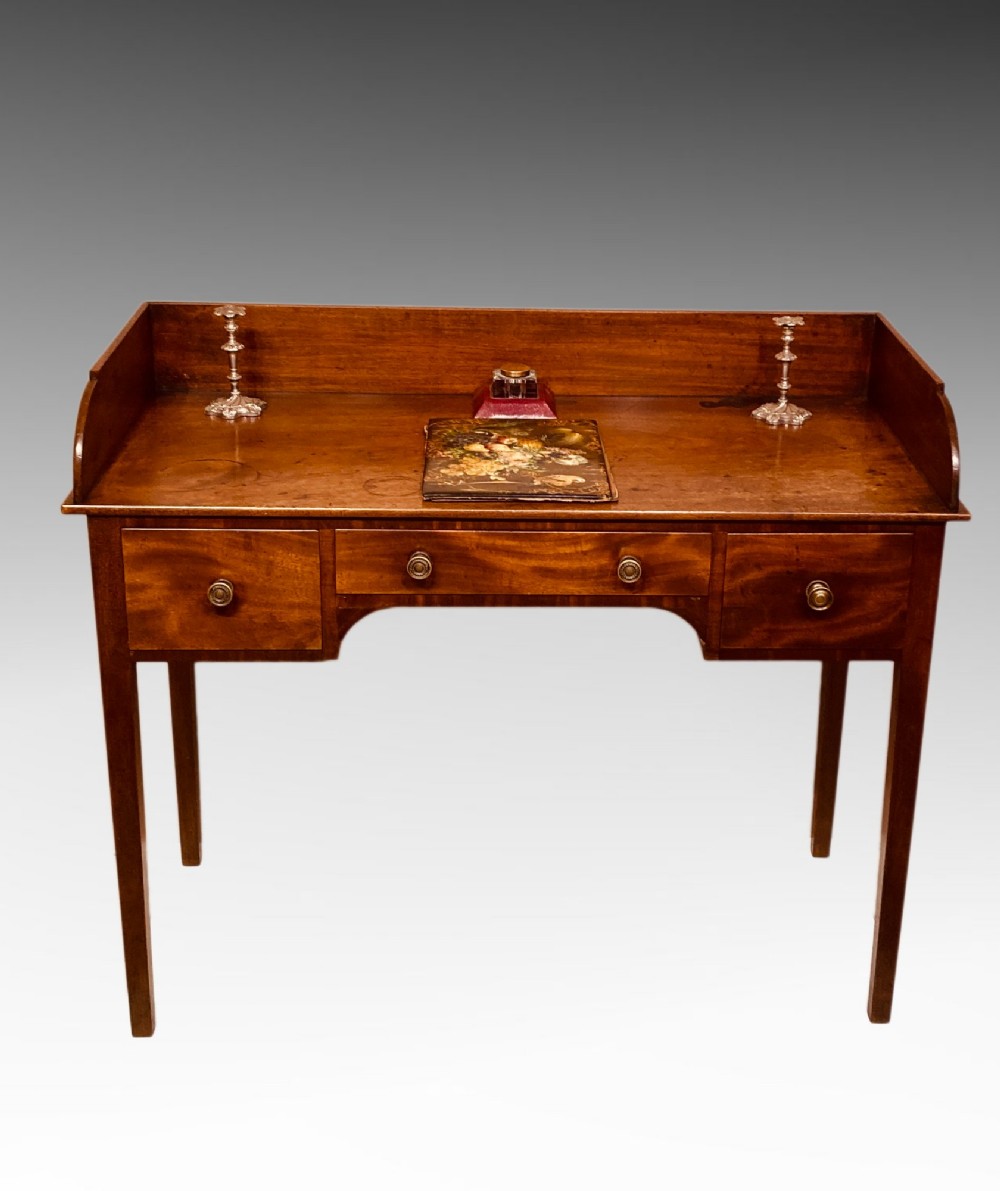 An antique Georgian mahogany side table featuring three drawers, brass knob handles, an upstand gallery back, and straight tapered legs.