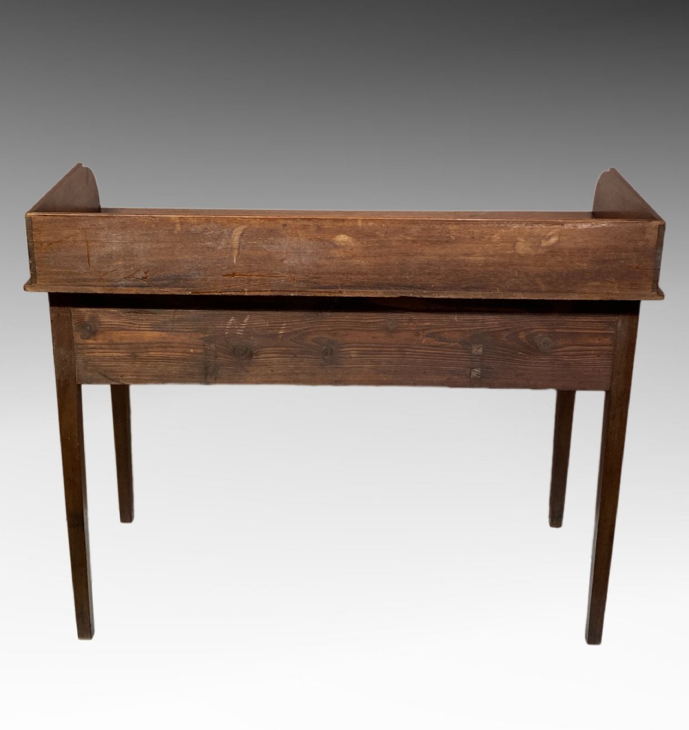 An antique Georgian mahogany side table featuring three drawers, brass knob handles, an upstand gallery back, and straight tapered legs. View II