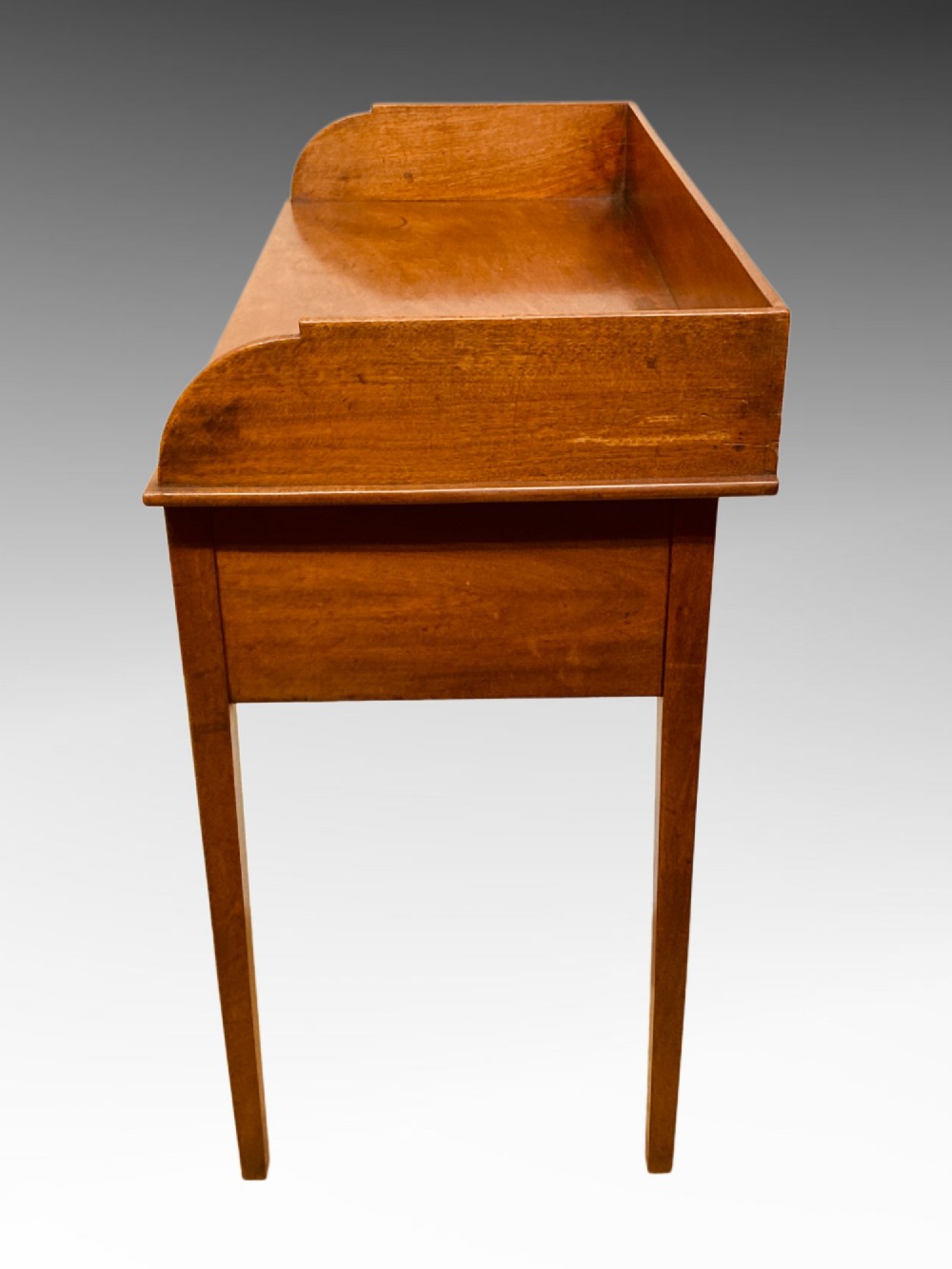 An antique Georgian mahogany side table featuring three drawers, brass knob handles, an upstand gallery back, and straight tapered legs. View III