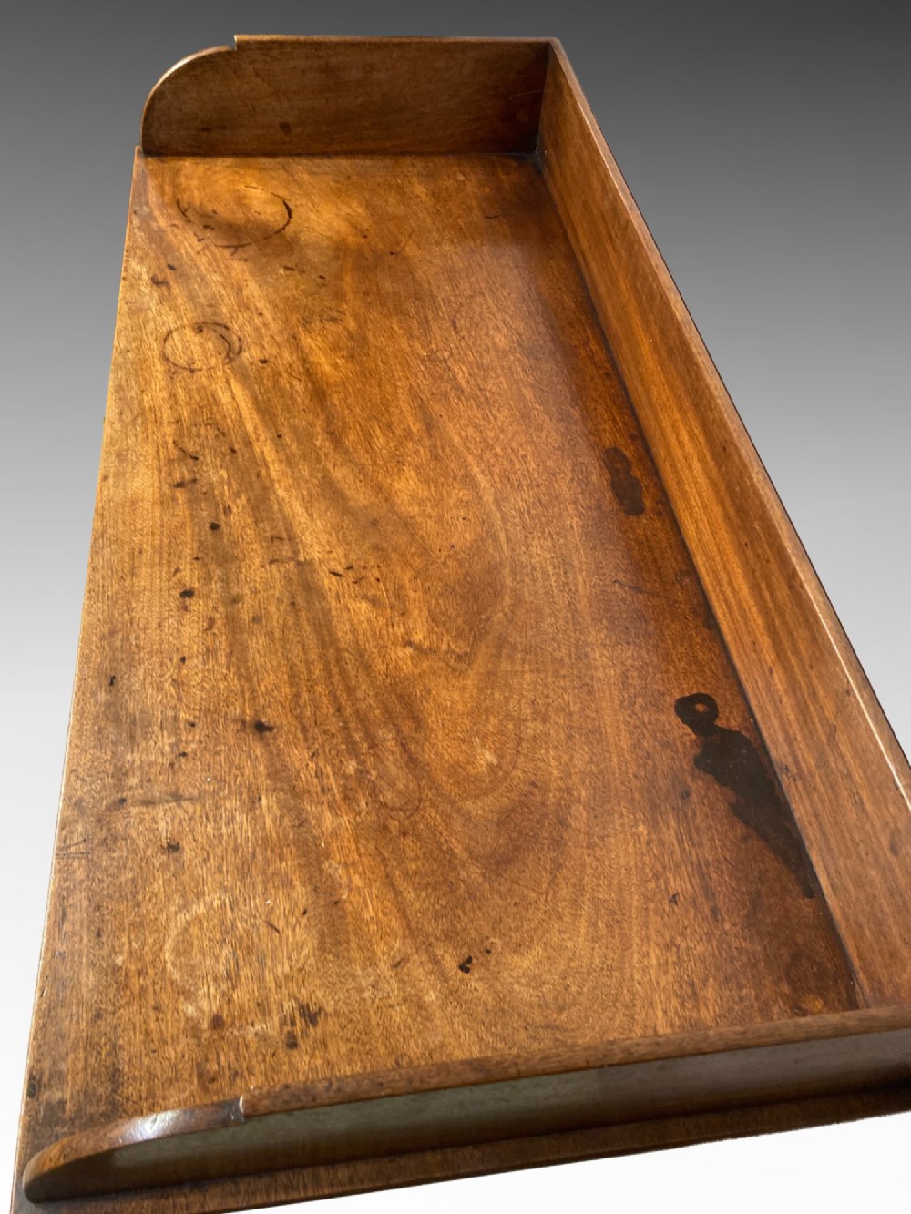 An antique Georgian mahogany side table featuring three drawers, brass knob handles, an upstand gallery back, and straight tapered legs. View V