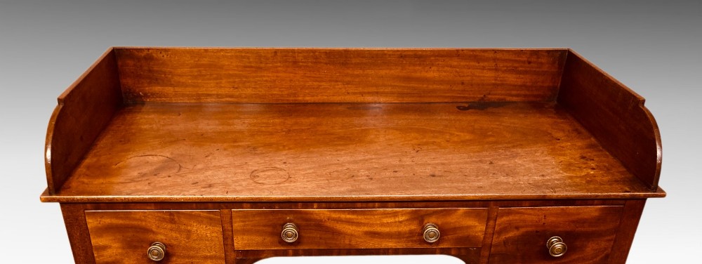 An antique Georgian mahogany side table featuring three drawers, brass knob handles, an upstand gallery back, and straight tapered legs. View VI