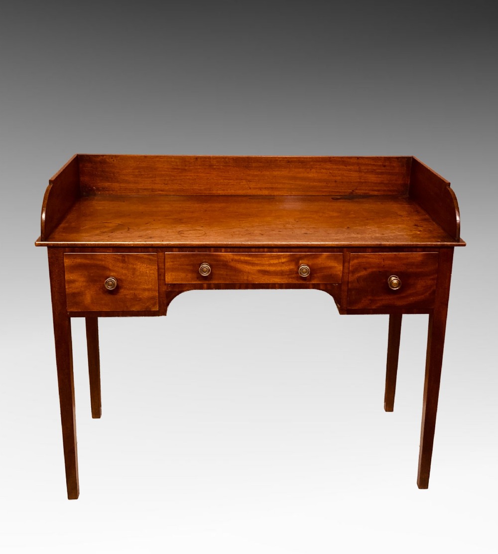 An antique Georgian mahogany side table featuring three drawers, brass knob handles, an upstand gallery back, and straight tapered legs. View VII