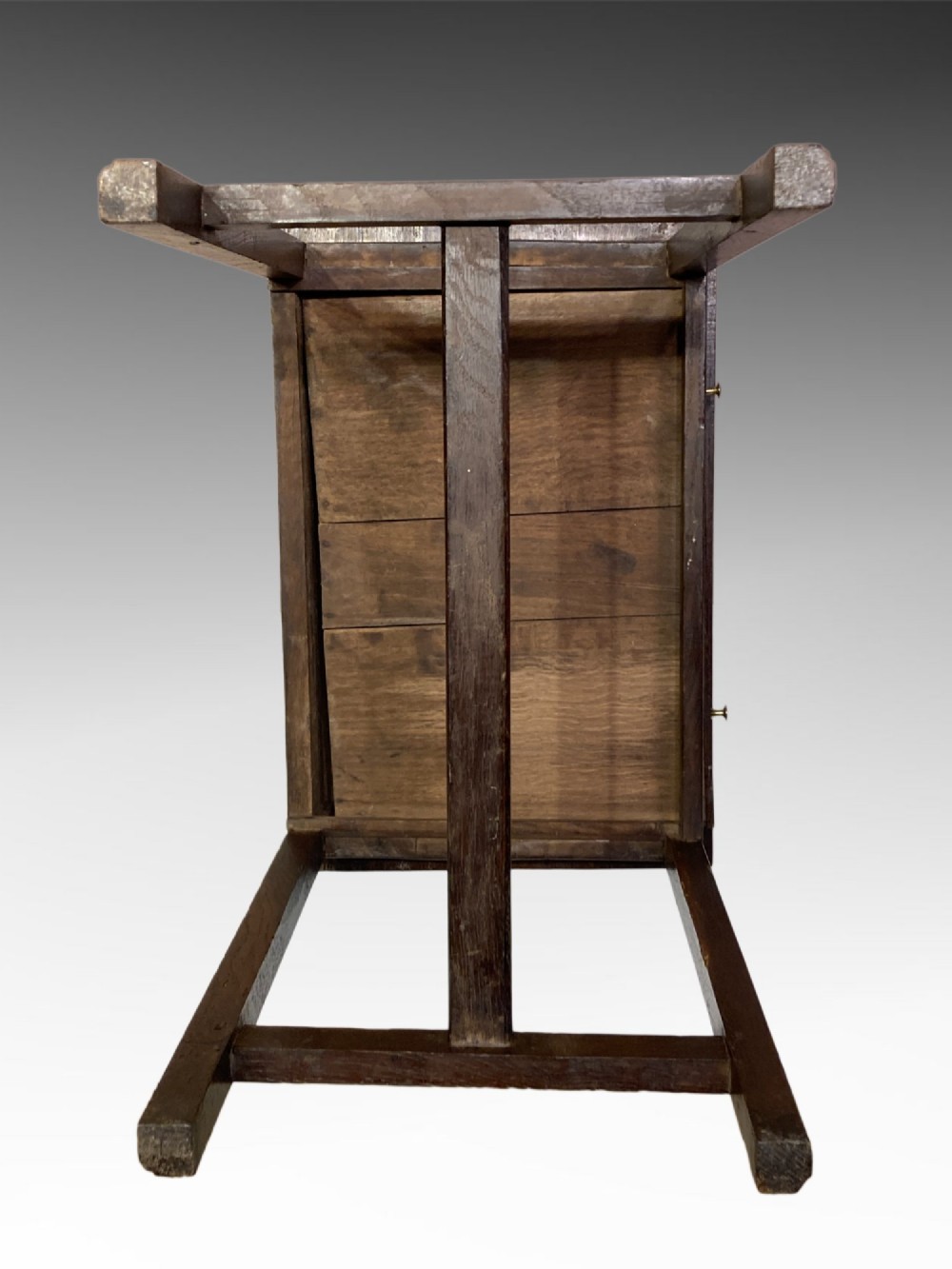 An antique dark oak side table featuring a single drawer with two small brass knobs and square legs connected by stretchers. View II