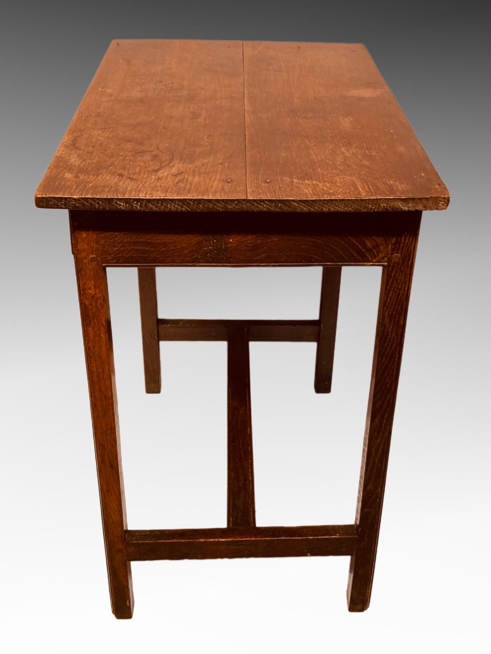 An antique dark oak side table featuring a single drawer with two small brass knobs and square legs connected by stretchers. View IV