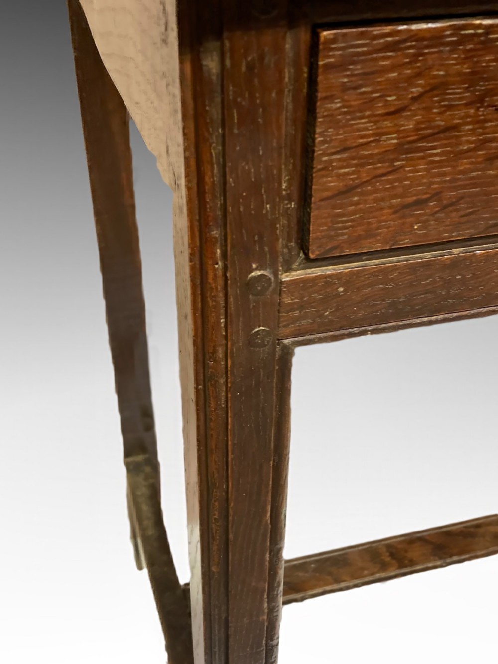 An antique dark oak side table featuring a single drawer with two small brass knobs and square legs connected by stretchers. View VIII
