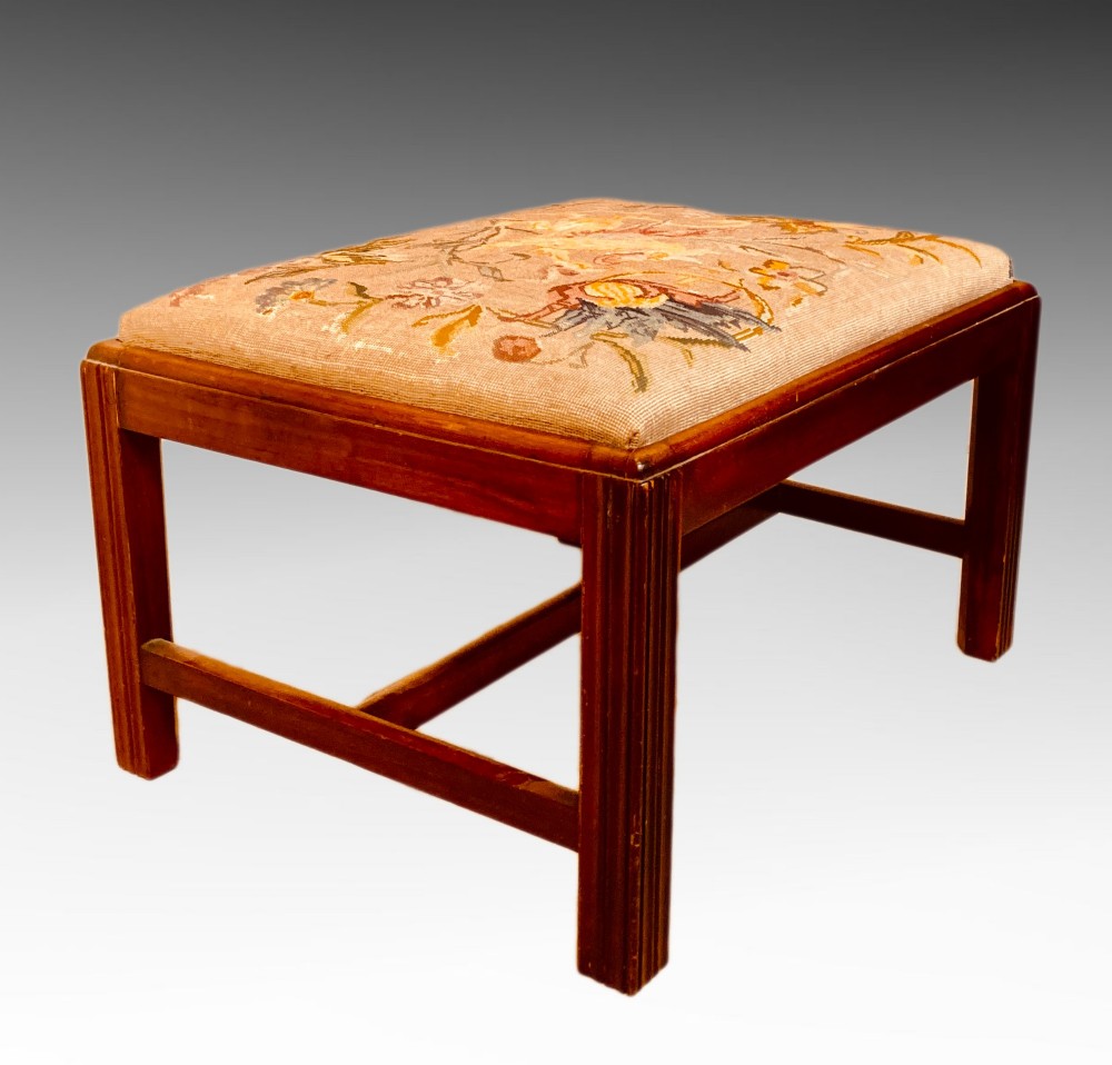 An antique mahogany rectangular dressing stool featuring fluted legs, an H-stretcher base, and a padded floral tapestry seat. View VI