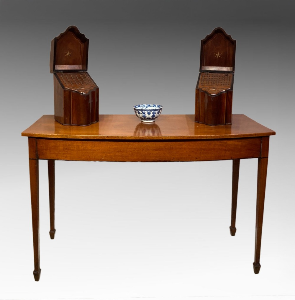 A Georgian mahogany side table featuring a gently curved bow front and four slender square-tapered legs terminating in spade feet. View VIII