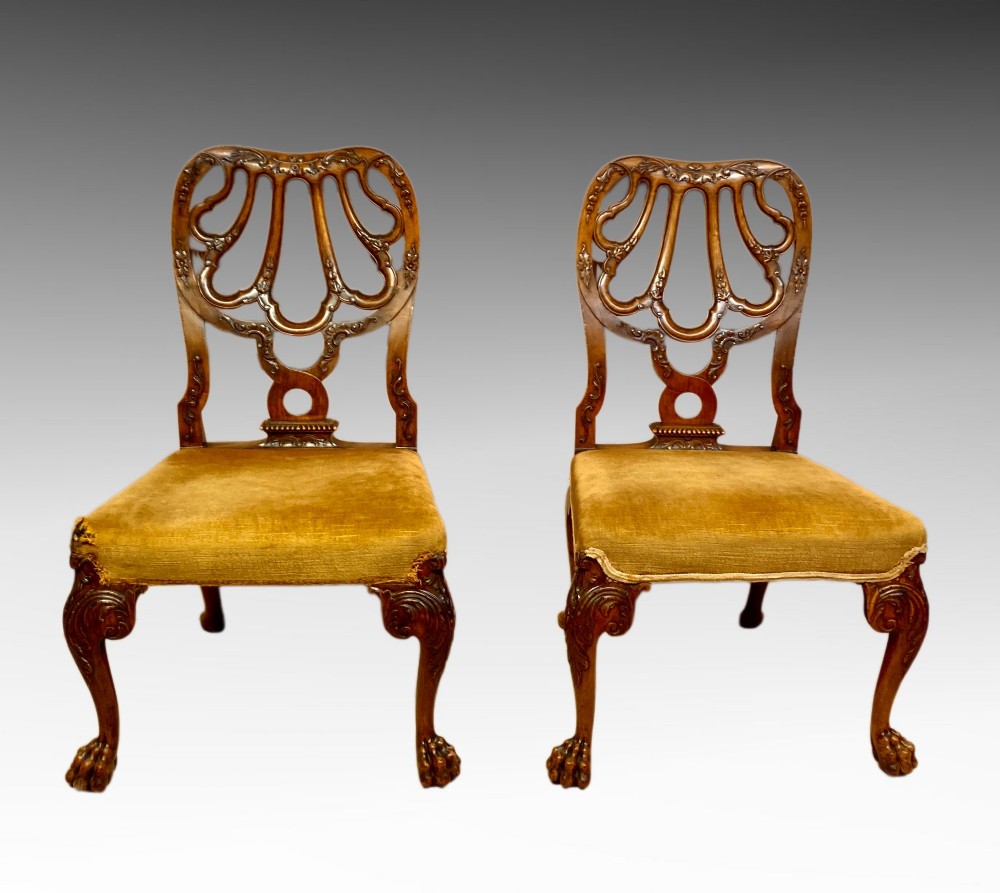 A pair of carved George II style walnut side chairs featuring open shell-form backs, upholstered gold velvet seats, and cabriole legs ending in ball and claw feet. View VIII