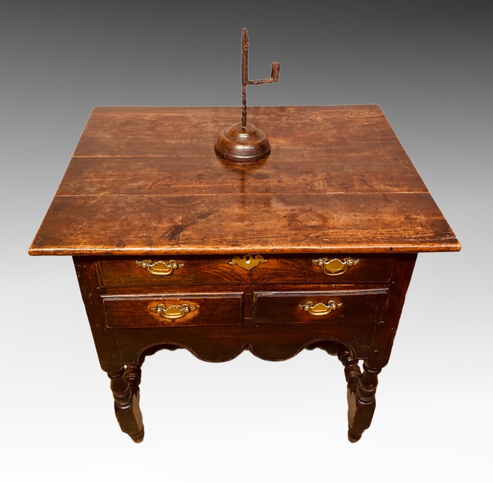 An antique dark elm Queen Anne side table featuring two small drawers with brass handles, a scalloped apron, turned legs, and cross stretchers. View II