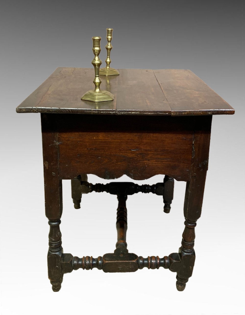 An antique dark elm Queen Anne side table featuring two small drawers with brass handles, a scalloped apron, turned legs, and cross stretchers. View III