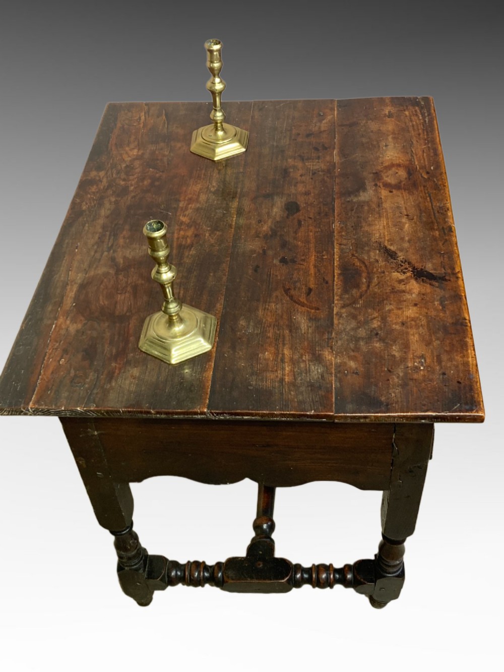 An antique dark elm Queen Anne side table featuring two small drawers with brass handles, a scalloped apron, turned legs, and cross stretchers. View IV