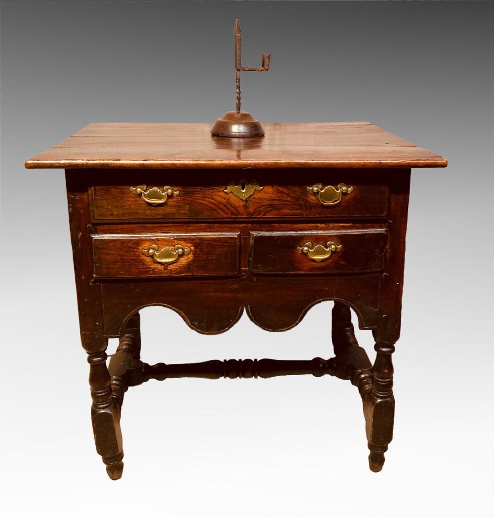 An antique dark elm Queen Anne side table featuring two small drawers with brass handles, a scalloped apron, turned legs, and cross stretchers. View V