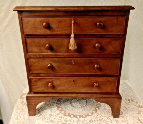 fig 1. A small mahogany chest of four drawers featuring turned wooden knob handles, keyholes, and a bracket foot base.